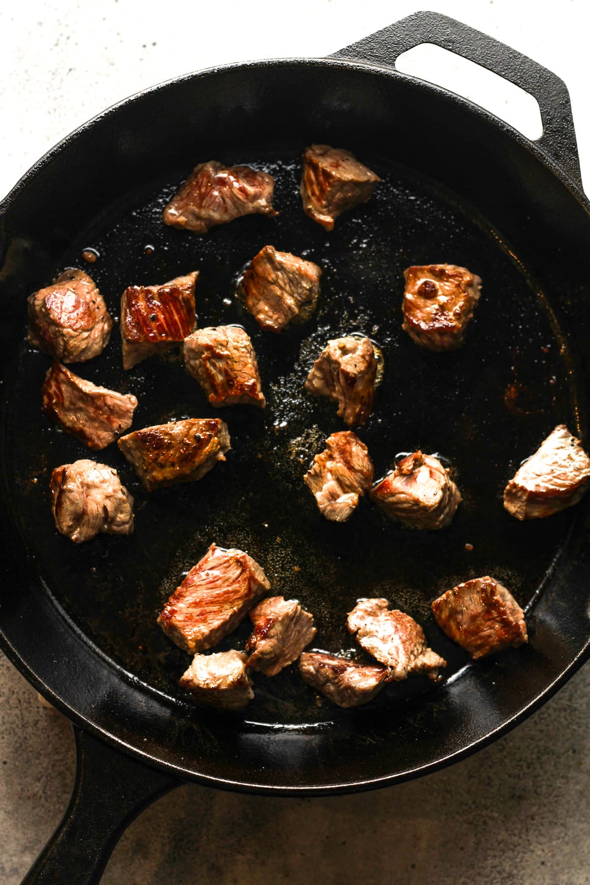 A skillet of the steak bites cooking.