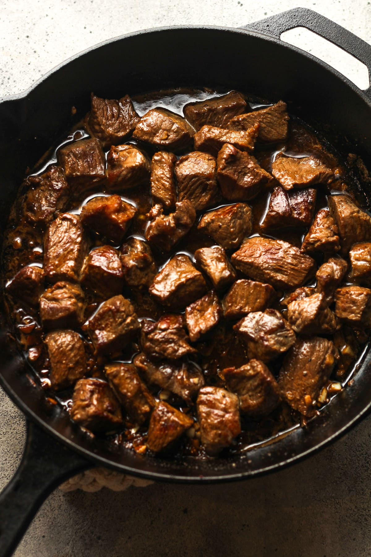 A skillet of the steak bites in garlic butter sauce.