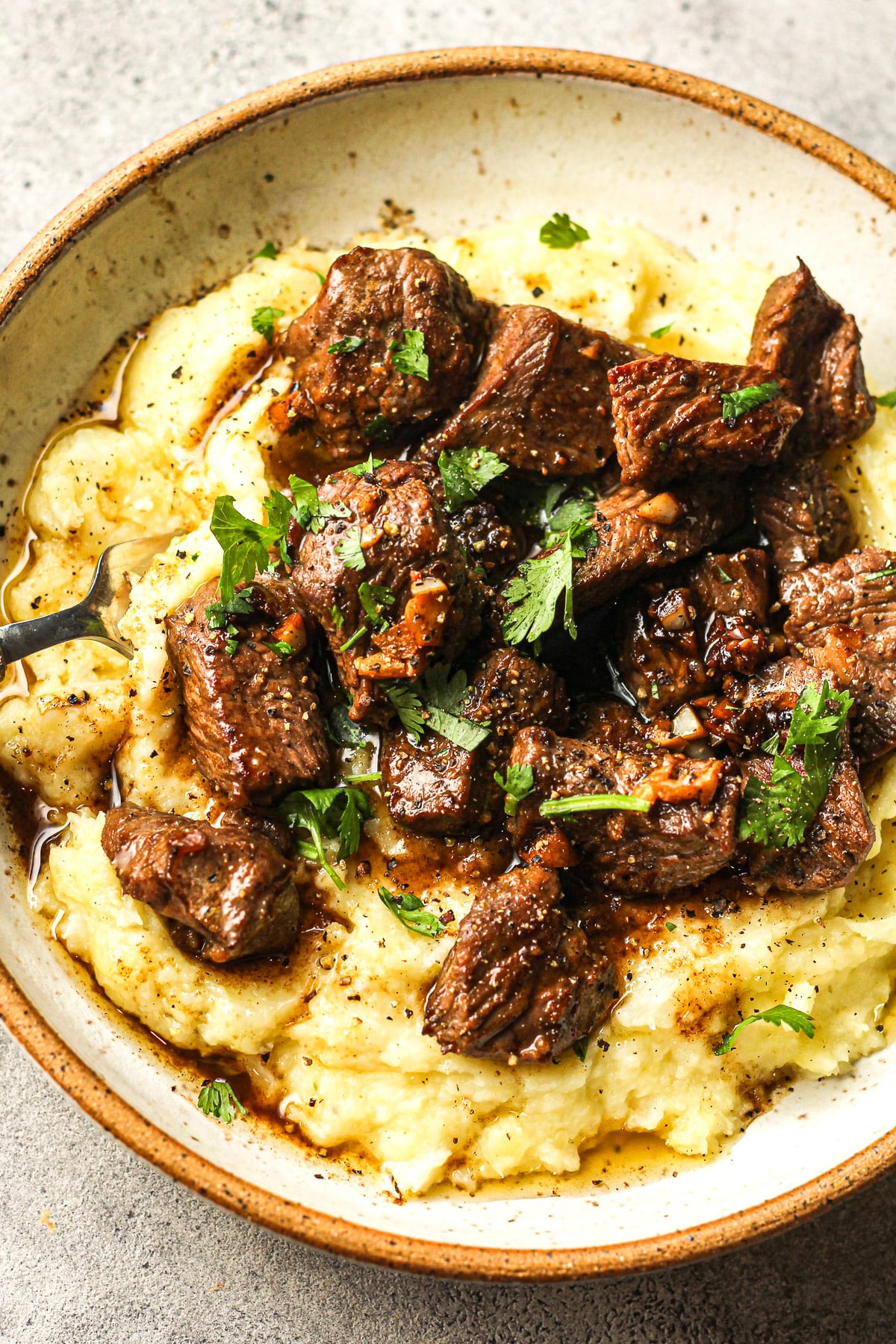 Closeup on a bowl of crispy steak bites over potato mash.