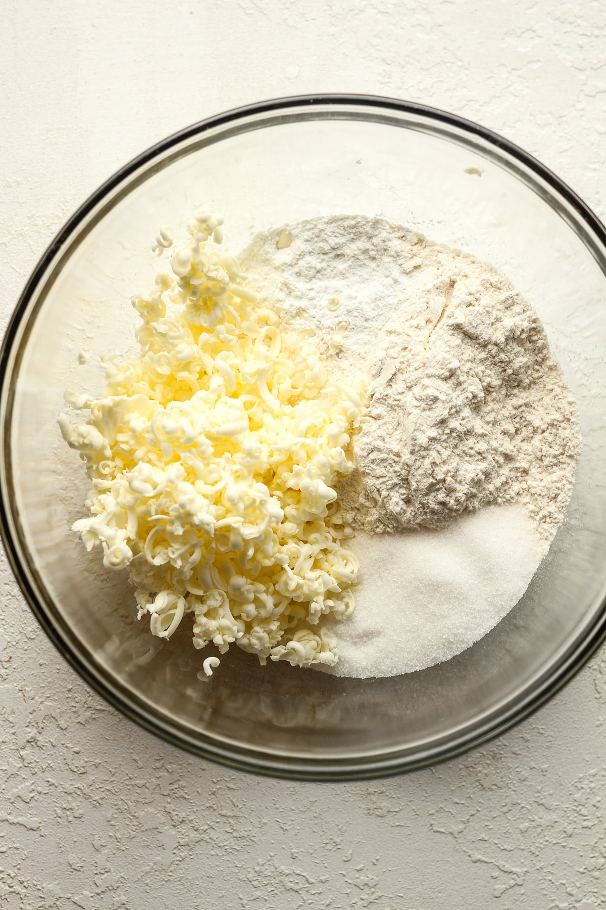 A bowl of the dry scone ingredients with frozen butter on top.