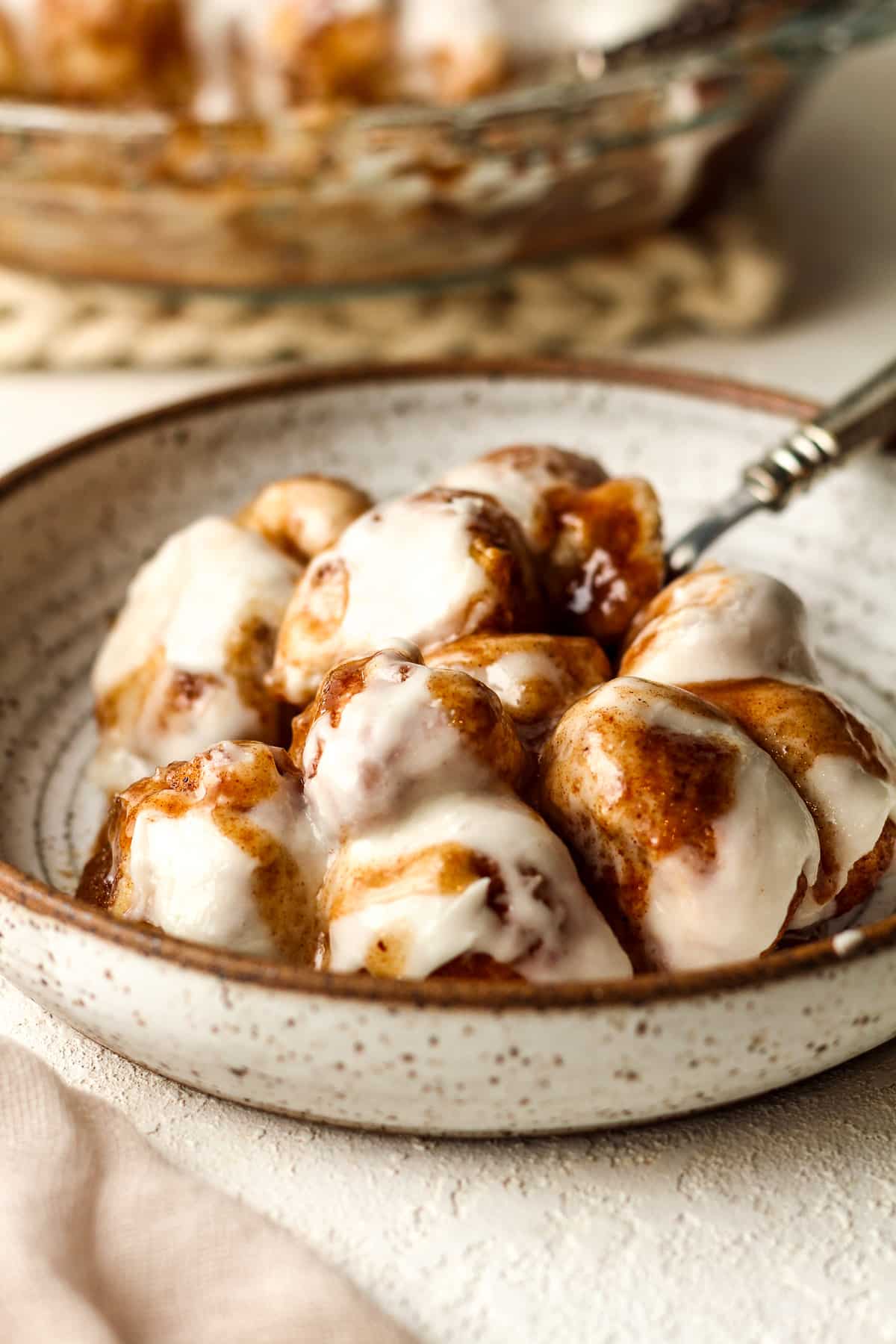 Side view of a bowl of cinnamon roll bites with a fork.