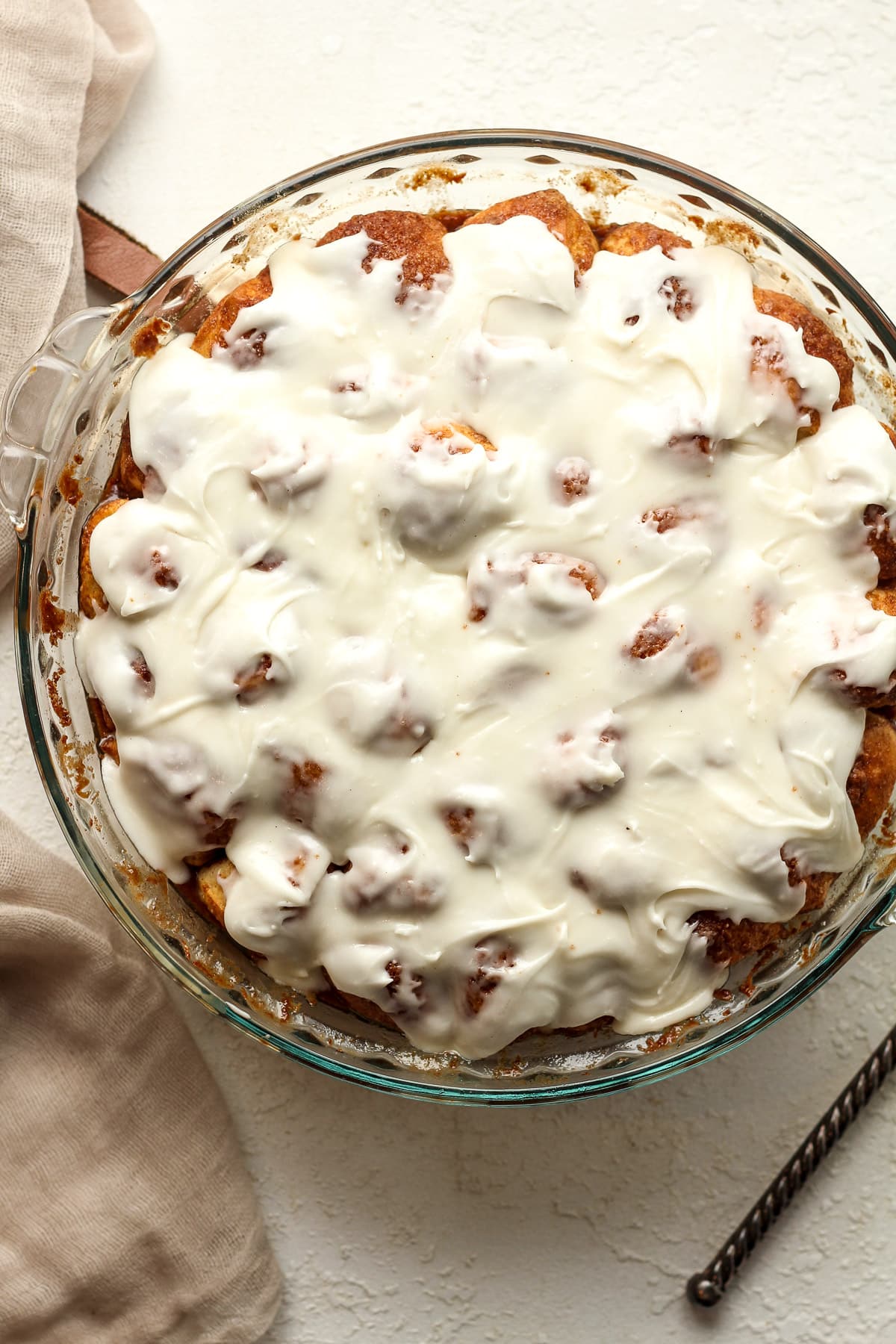 A pie dish of the baked and iced cinnamon roll bites.