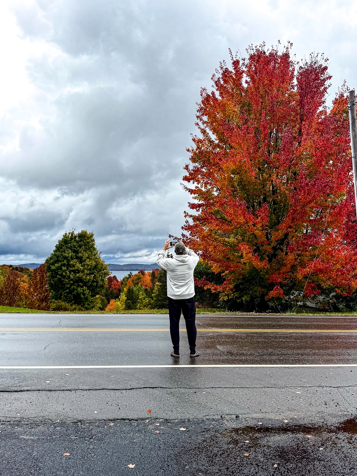 Mike standing on a wet road taking a photo of the foliage.