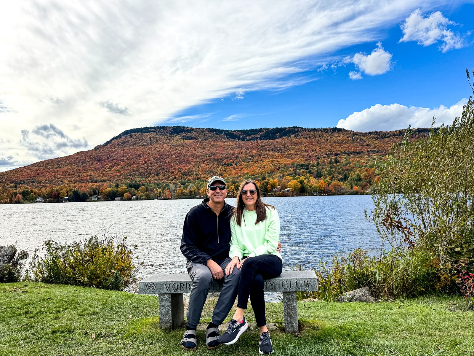 Mike and I sitting on a bench at Elmore Lake with the fall foliage in the background.