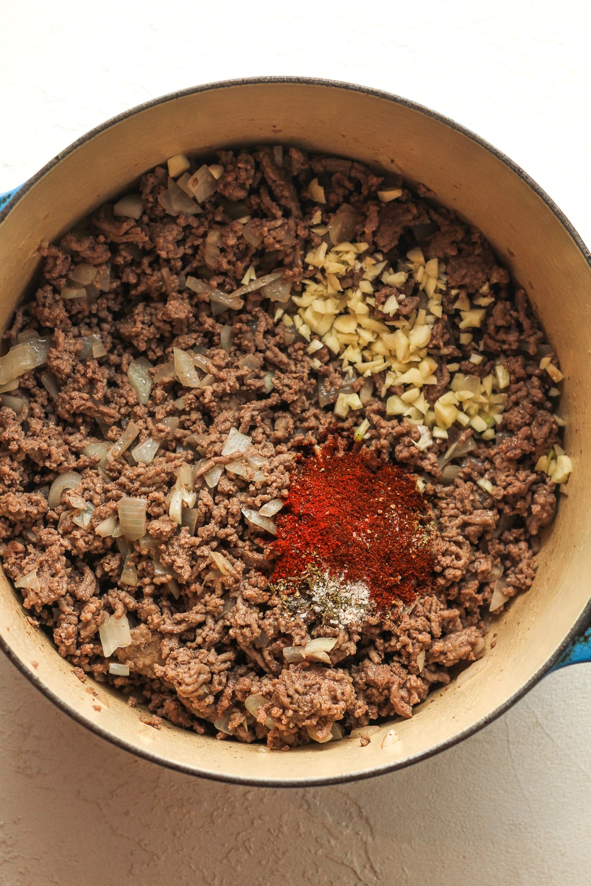 A pot of the browned beef and garlic plus seasonings on top.